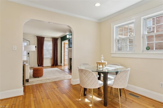 dining area with visible vents, arched walkways, baseboards, and hardwood / wood-style flooring