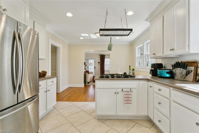 kitchen featuring arched walkways, light tile patterned floors, appliances with stainless steel finishes, and ornamental molding