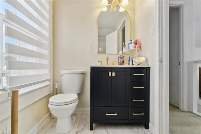 bathroom with vanity, toilet, baseboards, and marble finish floor