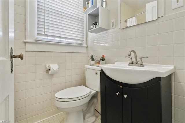 bathroom featuring tile patterned flooring, tile walls, toilet, and vanity