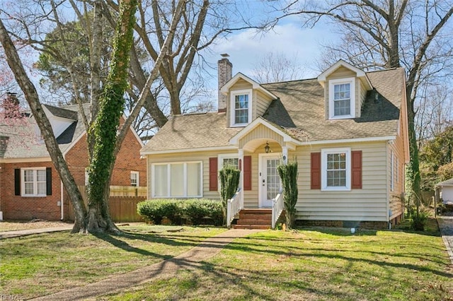 cape cod-style house featuring a shingled roof, a chimney, a front yard, and fence