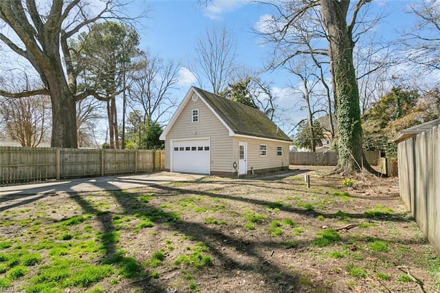 view of side of property with a fenced backyard, driveway, an outdoor structure, and a garage