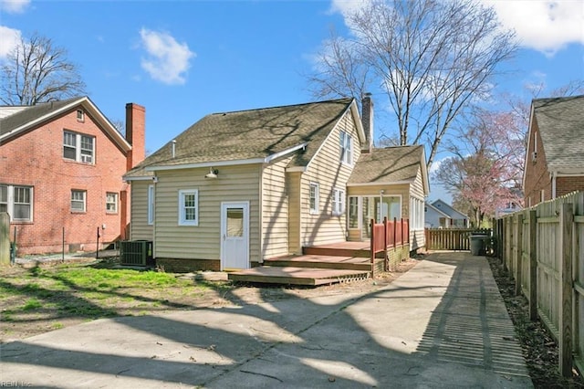 rear view of property featuring central AC unit, a deck, a chimney, and fence