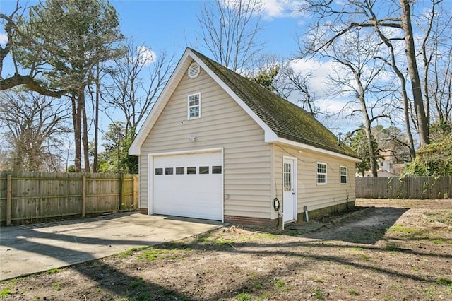 detached garage with concrete driveway and fence