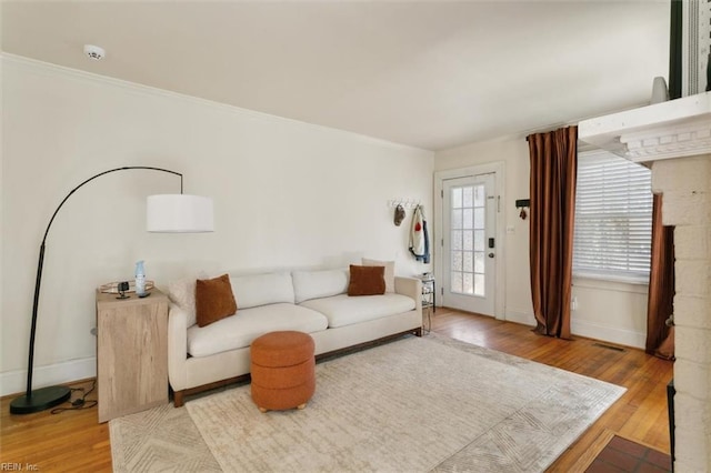 living area with visible vents, ornamental molding, baseboards, and wood finished floors