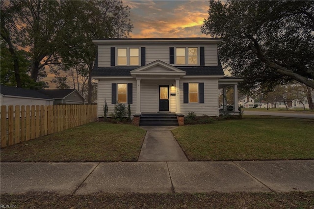 view of front of home with a lawn, a shingled roof, and fence