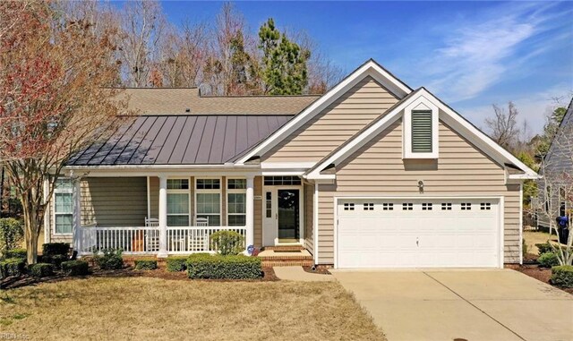 view of front facade featuring a standing seam roof, covered porch, concrete driveway, an attached garage, and metal roof