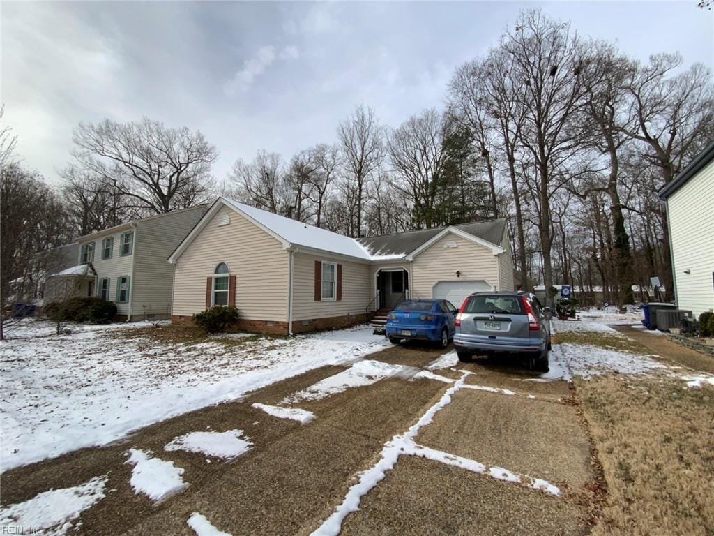 snow covered property featuring central AC, a garage, and driveway