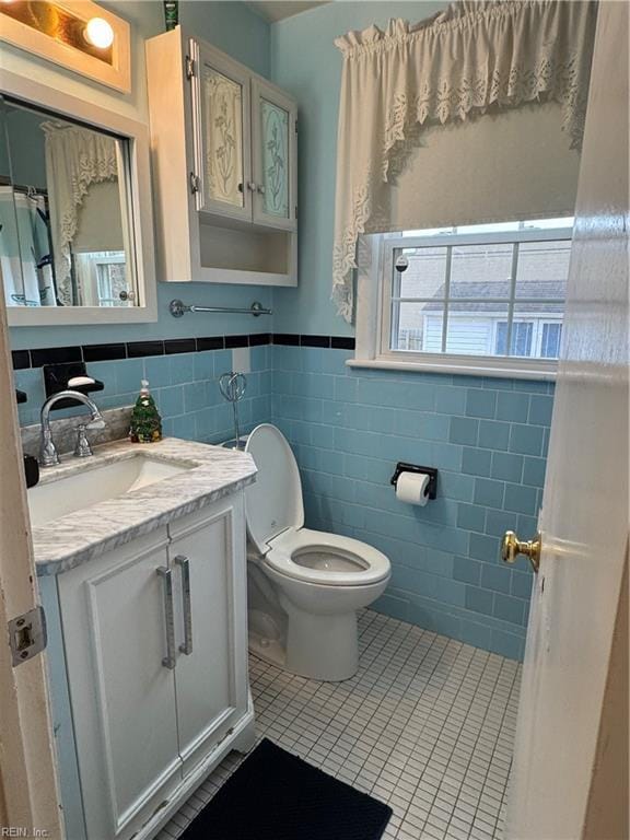 bathroom with vanity, a wainscoted wall, tile patterned floors, toilet, and tile walls