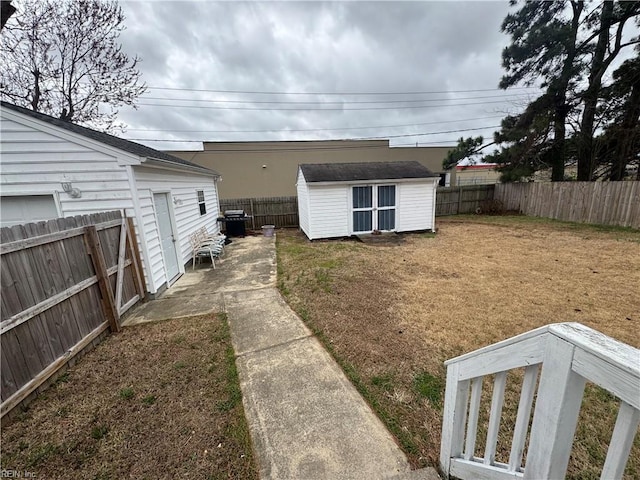 view of yard featuring a storage shed, an outbuilding, a fenced backyard, and a patio