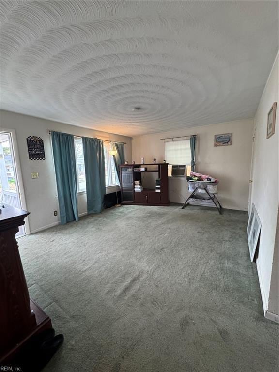 unfurnished living room with heating unit, a textured ceiling, a healthy amount of sunlight, and carpet flooring