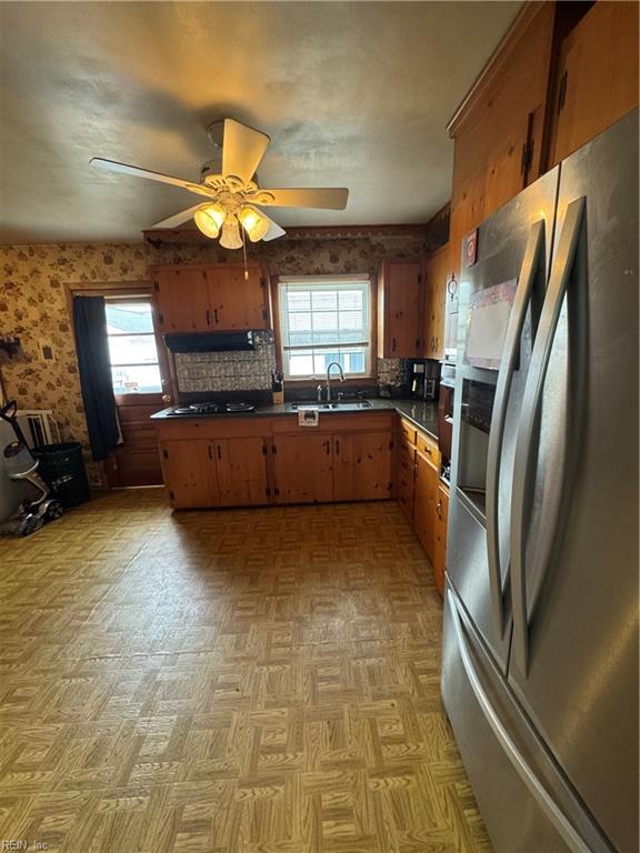 kitchen featuring a ceiling fan, stainless steel fridge with ice dispenser, under cabinet range hood, dark countertops, and backsplash