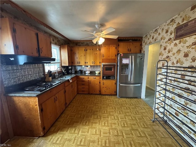 kitchen featuring wallpapered walls, ceiling fan, stainless steel fridge with ice dispenser, under cabinet range hood, and a sink