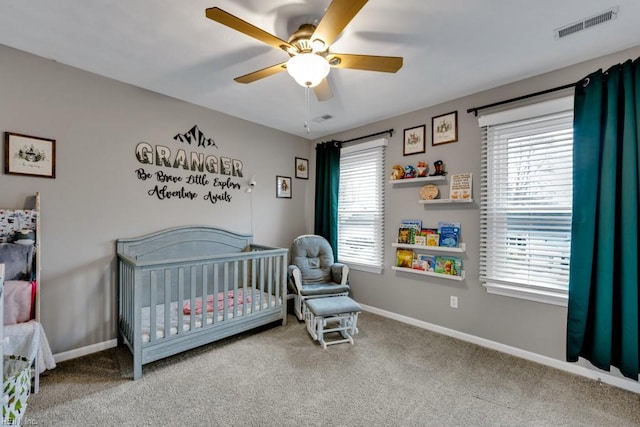 bedroom with a crib, carpet, visible vents, and baseboards