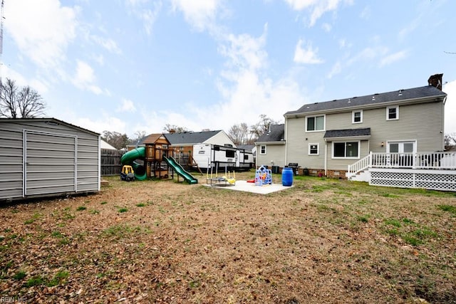 view of yard with a playground, fence, an outdoor structure, a patio area, and a storage unit