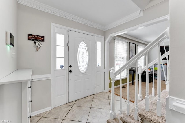 entrance foyer with tile patterned flooring, stairs, and crown molding