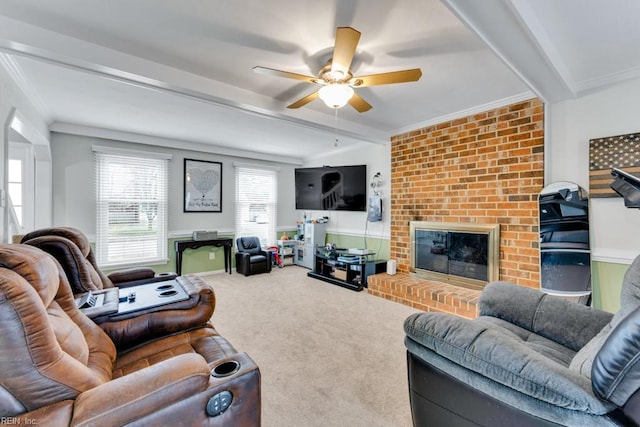 carpeted living room with a fireplace, beam ceiling, crown molding, and ceiling fan