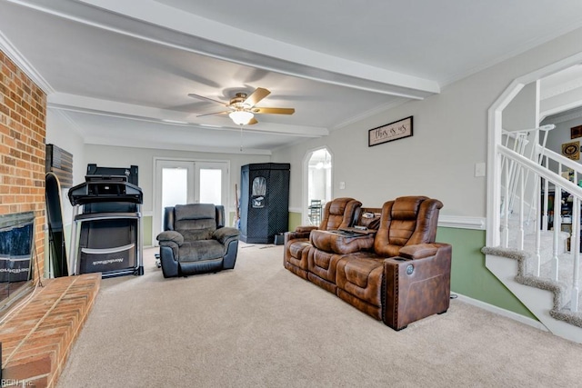 living room with beam ceiling, ornamental molding, arched walkways, carpet, and stairs