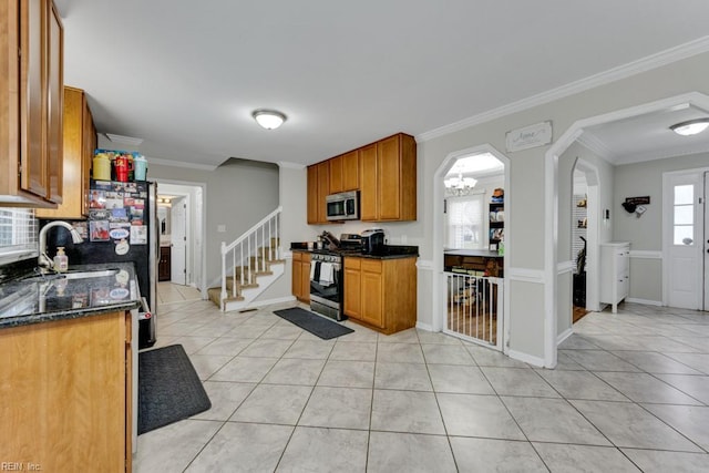 kitchen featuring light tile patterned floors, brown cabinetry, baseboards, stainless steel appliances, and crown molding