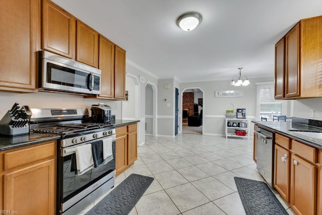 kitchen with arched walkways, a chandelier, appliances with stainless steel finishes, and ornamental molding