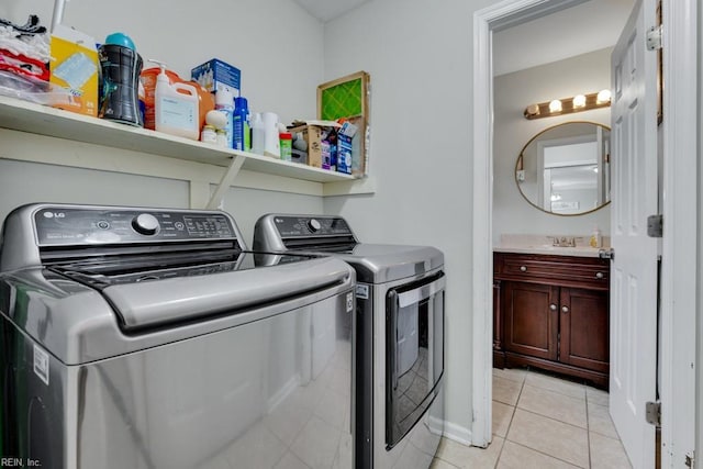 clothes washing area with a sink, light tile patterned flooring, laundry area, and washing machine and clothes dryer