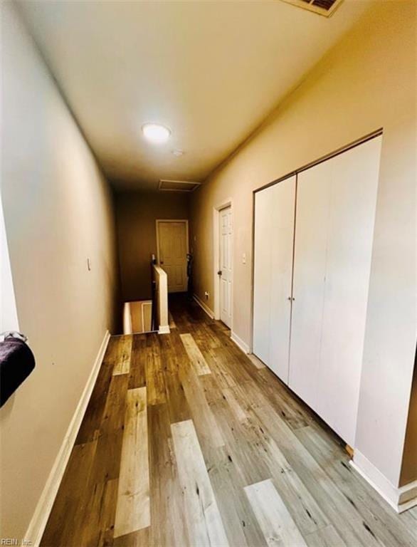 corridor featuring an upstairs landing, baseboards, and wood finished floors