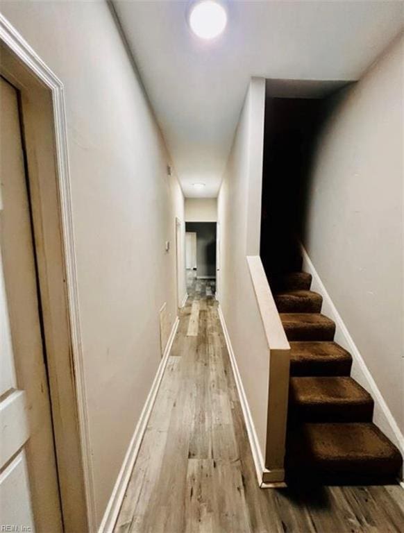 hallway with stairway, baseboards, and light wood-style flooring