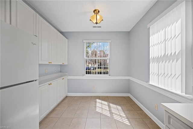 unfurnished dining area featuring light tile patterned floors, visible vents, and baseboards