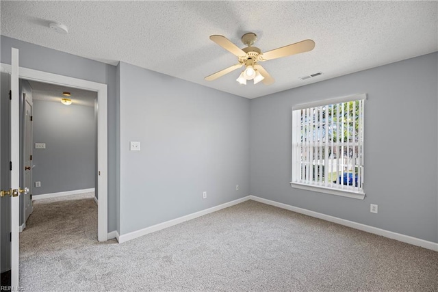 carpeted spare room with visible vents, a textured ceiling, baseboards, and ceiling fan