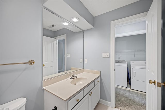 bathroom with visible vents, toilet, washer and clothes dryer, baseboards, and vanity