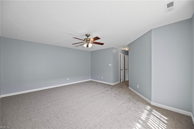 empty room with visible vents, a ceiling fan, a textured ceiling, carpet, and baseboards
