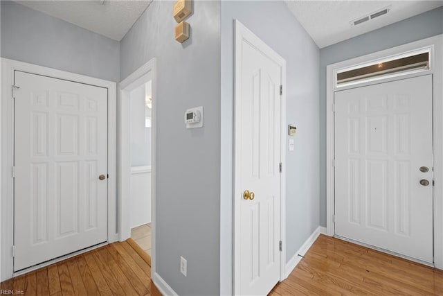foyer featuring a textured ceiling, visible vents, and light wood-type flooring
