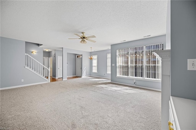 unfurnished living room featuring stairway, ceiling fan with notable chandelier, baseboards, and carpet floors