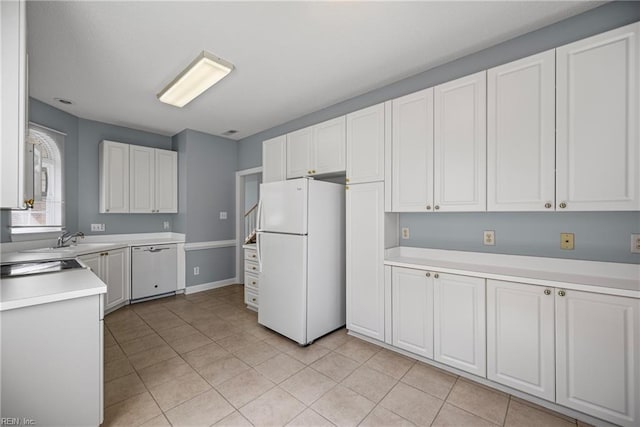 kitchen featuring white appliances, light tile patterned flooring, a sink, light countertops, and white cabinetry