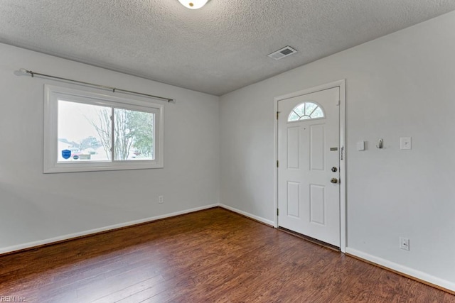 entryway featuring visible vents, baseboards, a textured ceiling, and wood finished floors