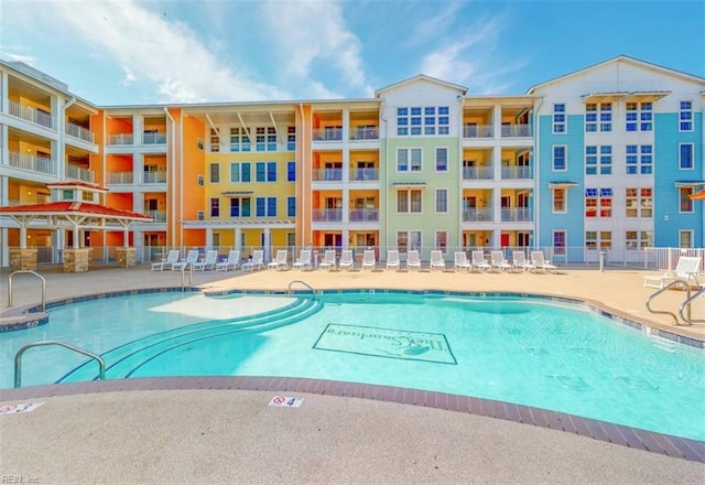 community pool with a patio area and fence