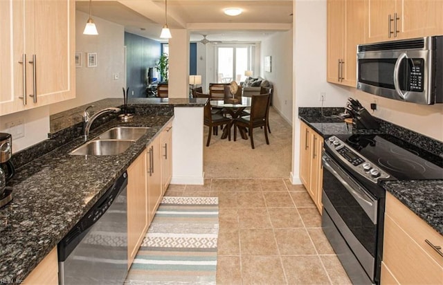 kitchen with dark stone countertops, light tile patterned flooring, ceiling fan, a sink, and appliances with stainless steel finishes