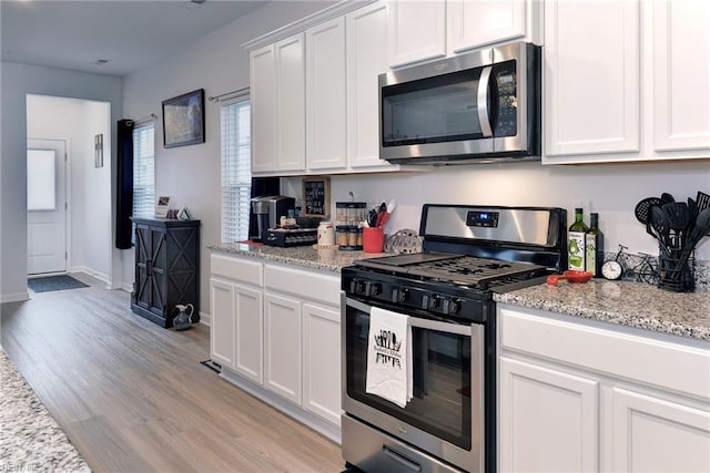 kitchen featuring stainless steel appliances, light wood-style flooring, and white cabinetry