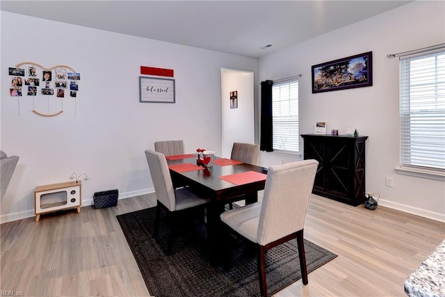 dining area featuring baseboards, light wood-style flooring, and stairs