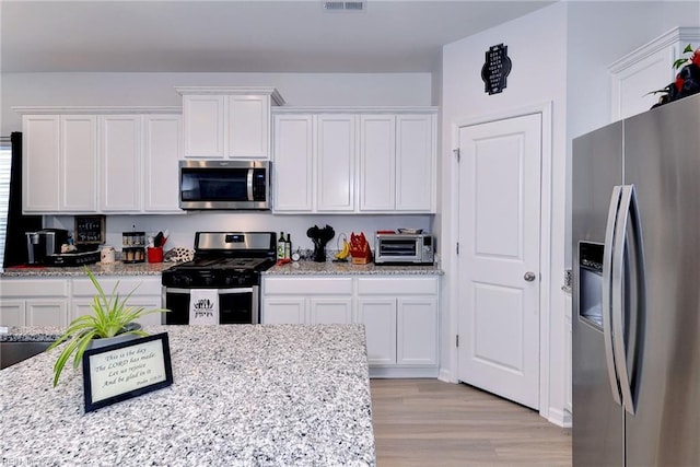 kitchen featuring white cabinets, appliances with stainless steel finishes, and light wood-style floors