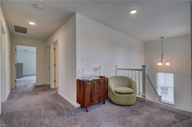 living area featuring carpet flooring, an upstairs landing, visible vents, baseboards, and an inviting chandelier