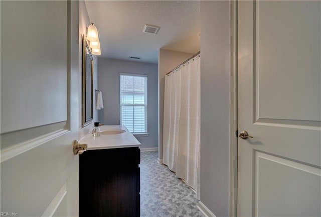 full bath with vanity, baseboards, a textured ceiling, visible vents, and curtained shower