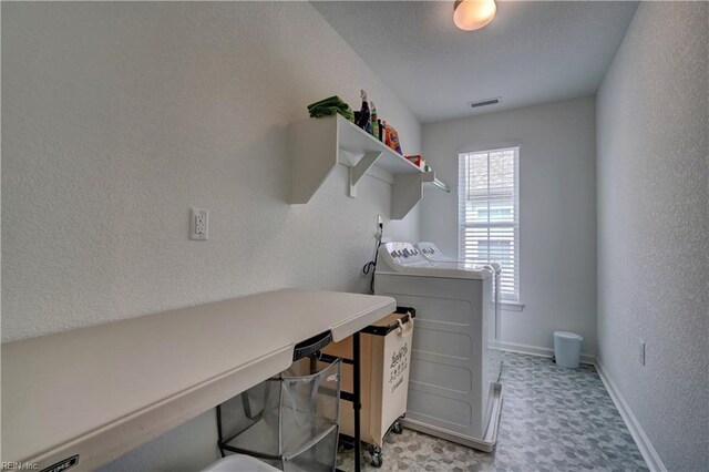 laundry area featuring a textured ceiling, independent washer and dryer, baseboards, laundry area, and a textured wall