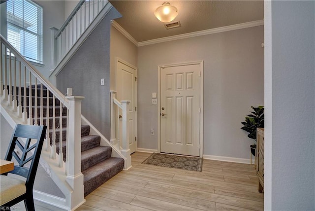 entrance foyer featuring stairs, light wood-type flooring, baseboards, visible vents, and ornamental molding