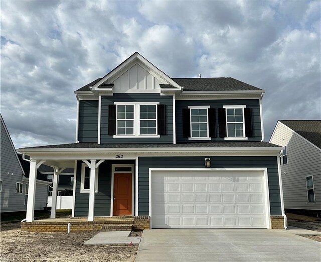 view of front of home with a porch, driveway, an attached garage, and board and batten siding