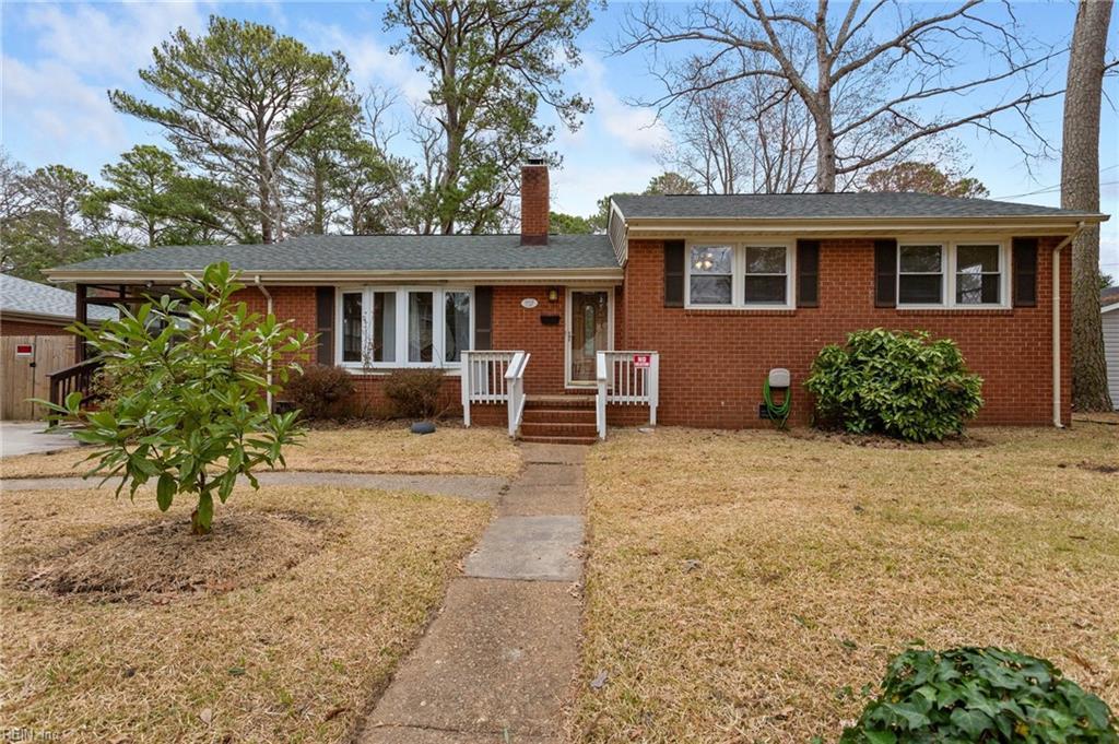 split level home featuring a front lawn, brick siding, and a chimney
