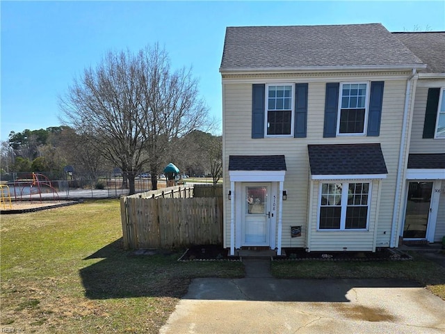 view of front of house with a shingled roof, a playground, a front lawn, and fence