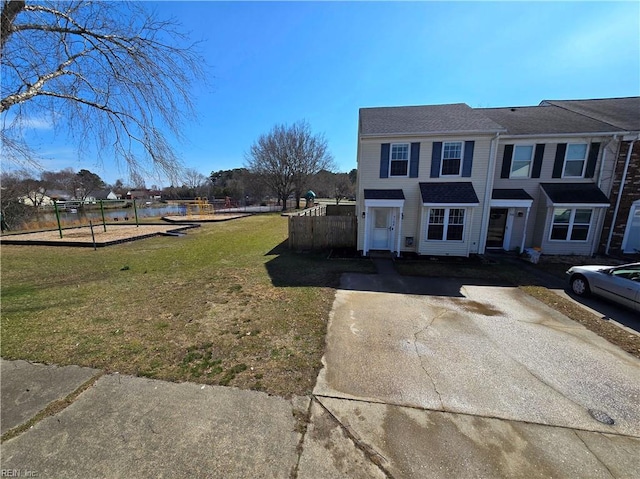 view of front of house with concrete driveway, a front lawn, and fence