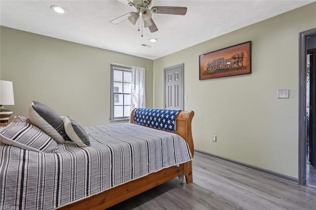bedroom with baseboards, recessed lighting, wood finished floors, and visible vents