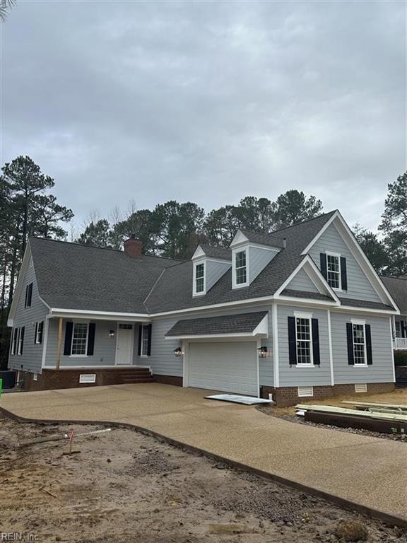 view of front of house with cooling unit, concrete driveway, a shingled roof, a garage, and a chimney